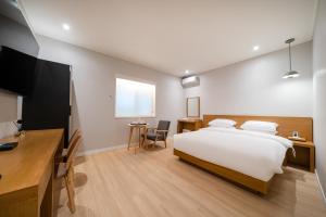 a bedroom with a bed and a desk and a television at MONO HOTEL in Suwon