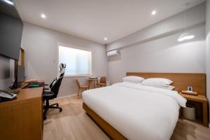 a bedroom with a large white bed and a desk at MONO HOTEL in Suwon