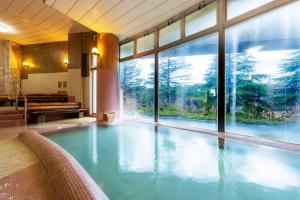 a swimming pool in a building with a large window at Hotel Yutoria Fujisato in Fujisato