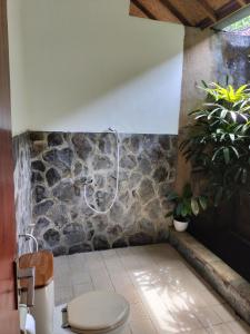 a bathroom with a shower in a stone wall at Bayumantra Bungalows in Lovina