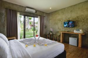 a bedroom with a white bed with a swan on it at Bali Breezz Hotel in Jimbaran