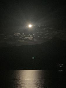 una luna llena elevándose sobre el agua por la noche en CASA ENSUEÑO, en Isla de La Pacanda