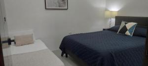 a bedroom with a bed with a blue comforter at cr.arenalapartments#3 hermoso lugar con parqueo in Fortuna