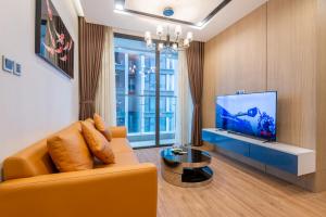 a living room with a yellow couch and a tv at NVT Housing - Vinhomes Metropolis Apartment Hanoi in Hanoi
