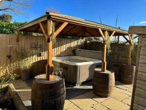 uma banheira de hidromassagem sob uma pérgola de madeira com dois barris em old school house em Skipton