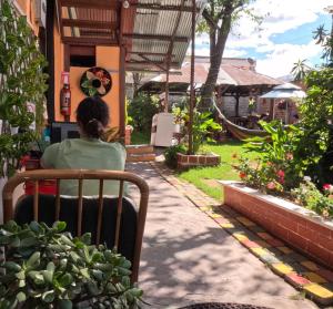 una mujer sentada en una silla frente a una casa en Colonial House Inn en Quito