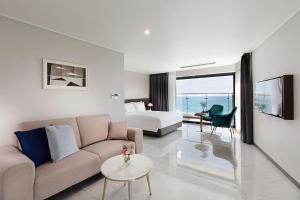 a living room with a couch and a bed at Haeundae Youngmu Parade Hotel in Busan