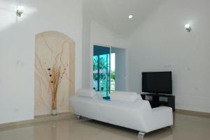 sala de estar con sofá blanco y TV en Quinta vacacional completa, en Villavicencio