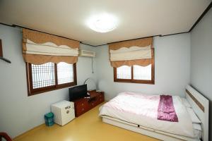a bedroom with a bed and a tv in it at Jun Motel in Jeju
