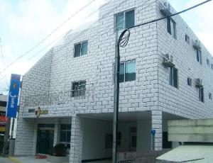 een wit bakstenen gebouw met een straatlicht ervoor bij Jun Motel in Jeju-stad