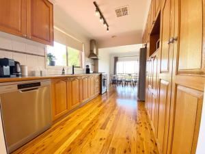 a kitchen with wooden cabinets and a wooden floor at Glens Haven with Lakeviews and Outdoor Firepit in Wagga Wagga