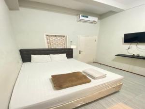 een slaapkamer met een wit bed met een bruine deken erop bij Treebox in Ngadipuro