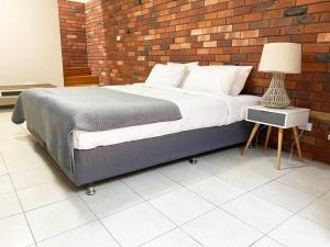 a bedroom with a large bed with a brick wall at Glens Haven with Lakeviews and Outdoor Firepit in Wagga Wagga +3 photos