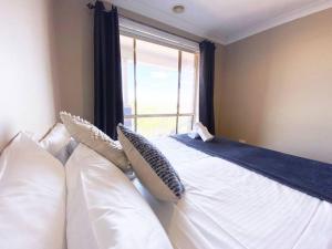 a bedroom with a bed with pillows and a window at Glens Haven with Lakeviews and Outdoor Firepit in Wagga Wagga