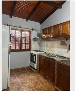 a kitchen with wooden cabinets and a white refrigerator at Parana house in Puerto Iguazú