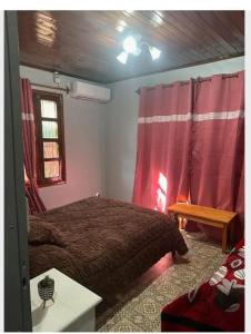 - une chambre avec un lit et des rideaux rouges dans l'établissement Parana house, à Puerto Iguazú