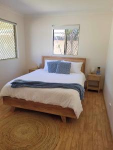 a bedroom with a large bed with blue pillows at G&R Beach Cottage in Warnbro