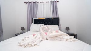 dwa łabędzie owinięte w ręczniki siedzące na łóżku w obiekcie Sky Blue w mieście Jarabacoa
