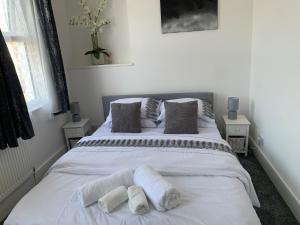 a bedroom with a white bed with two pillows at L A PLACE Croydon, London in Norwood