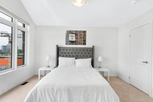 1 dormitorio blanco con 1 cama grande y 2 ventanas en Tulip Smartments Brampton-Spacious 4 Bedroom Near Airport, en Brampton