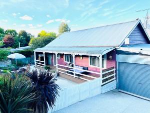 ein rosafarbenes Haus mit einer Veranda und einer Garage in der Unterkunft The Garden Cottage in Tawonga