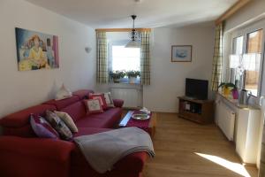 ein Wohnzimmer mit einem roten Sofa und einem TV in der Unterkunft Ferienwohnungen Haus Kunterbunt in Berchtesgaden