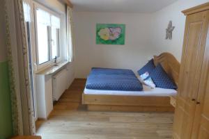 Schlafzimmer mit einem Bett mit blauer Bettwäsche und einem Fenster in der Unterkunft Ferienwohnungen Haus Kunterbunt in Berchtesgaden