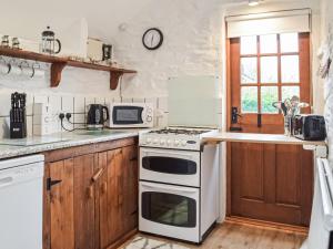 a kitchen with a stove and a microwave at Y Beudy - Uk46191 in Llanybydder