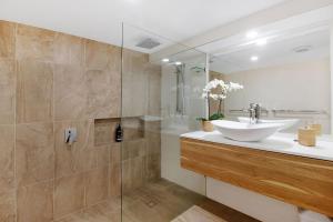 a bathroom with a sink and a glass shower at Oceanfront Beach House On Marine Parade in Kingscliff