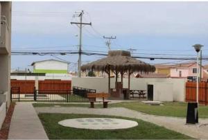 un parque con mesa de picnic y sombrilla de paja en Departamento verano la serena, en La Serena