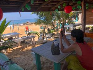 a woman sitting at a picnic table on the beach at Ceylon Beach Home in Galle