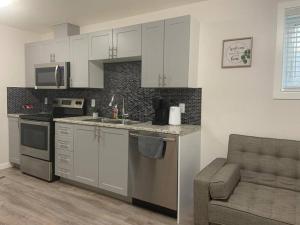cocina con armarios blancos, fregadero y sofá en Guest Suite with Queen Bed -Home Away from Home, en Regina 8 fotos más