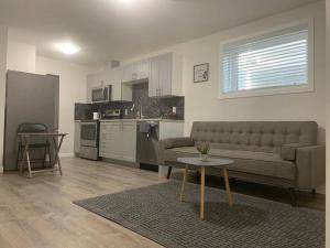 Una sala de estar con un sofá y una mesa y una cocina. en Guest Suite with Queen Bed -Home Away from Home, en Regina