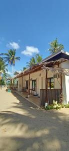 a building on the beach with palm trees at CocoHut Beach House in Locaroc