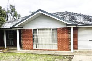 a red brick house with a large window at Suburban Bliss - Elegant Villa 1 in Wagga Wagga