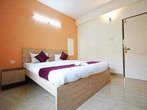 ein Schlafzimmer mit einem großen Bett mit lila Kissen in der Unterkunft Hotel Ashiana Lagoon in Puri