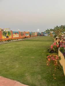 ein Grasfeld mit einem Zug im Hintergrund in der Unterkunft Hotel Ashiana Lagoon in Puri