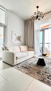 a white living room with a couch and a table at Cozy Central Apt with Parking and Skyline View in Dubai