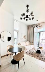 a white living room with a table and a couch at Cozy Central Apt with Parking and Skyline View in Dubai