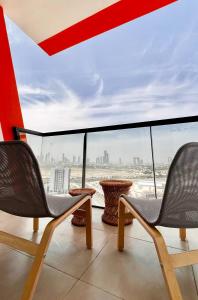 a balcony with two chairs and a view of the city at Cozy Central Apt with Parking and Skyline View in Dubai
