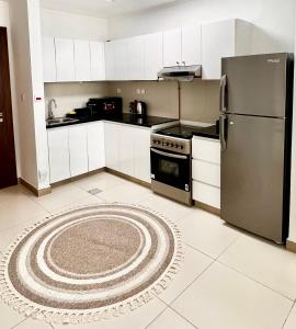 a kitchen with a refrigerator and a rug on the floor at Cozy Central Apt with Parking and Skyline View in Dubai