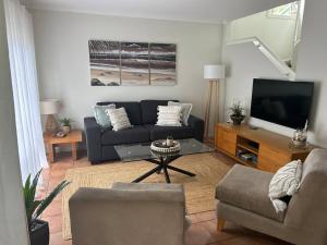 a living room with a couch and a tv at Beach Haven @ Diggers in Coffs Harbour
