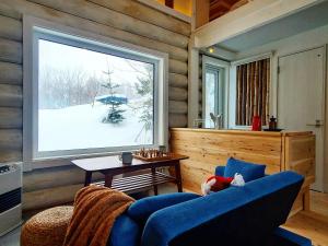- un salon avec un canapé bleu et une grande fenêtre dans l'établissement 真狩村焚き火キャンプ場, à Makkari