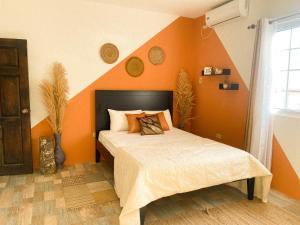 a bedroom with a bed with an orange wall at House of Zen in Santa Cruz
