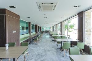 - une salle à manger avec des tables, des chaises et des fenêtres dans l'établissement PhetPhangan Hotel, à Ban Tha Kup