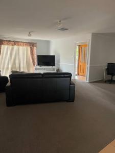 a living room with a black couch and a television at Suburban Bliss - Elegant Villa 2 in Wagga Wagga