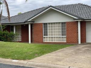 a red brick house with a large window at Suburban Bliss - Elegant Villa 2 in Wagga Wagga
