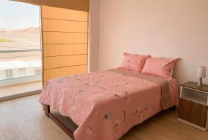 um quarto com uma cama rosa e uma grande janela em South Beach GH Tacna em Tacna