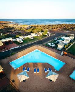 an overhead view of a swimming pool with chairs and the ocean at Kalbarri Red Bluff Tourist Park in Kalbarri