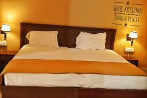 a large bed in a hotel room with two lamps at OYO HOTEL SHREE KRISHNA JUNGLE RESORT KHAJURAHO in Khajurāho
